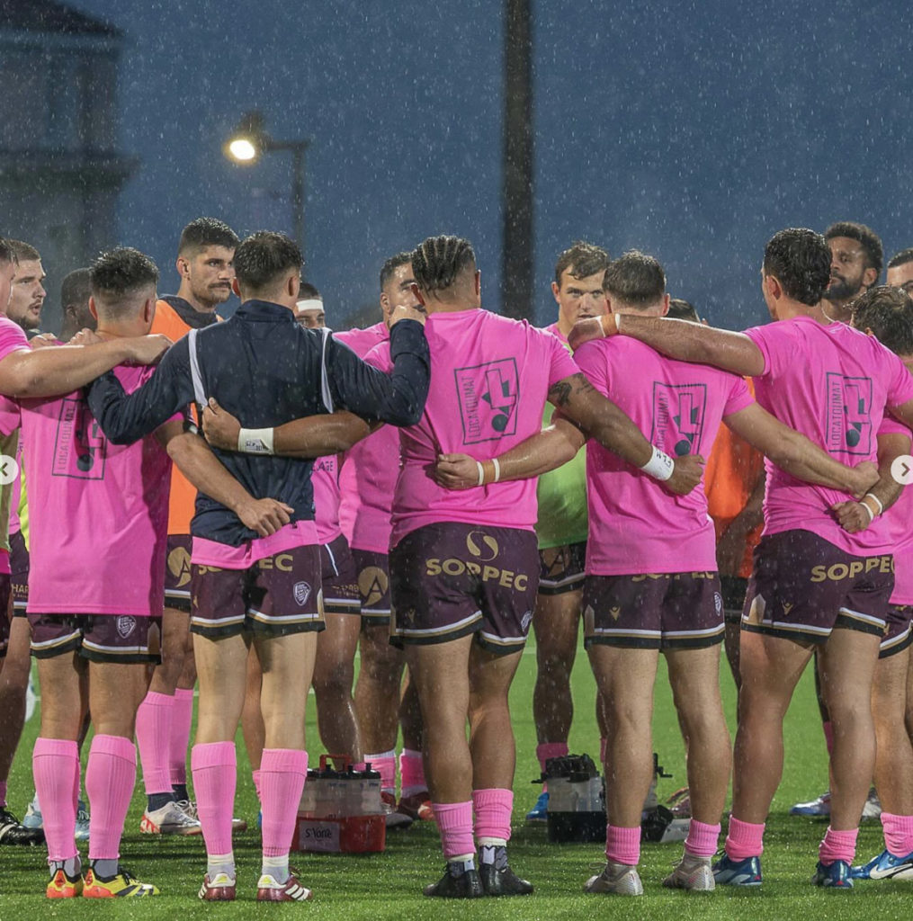 Équipe de rugby s'embrassant sous la pluie