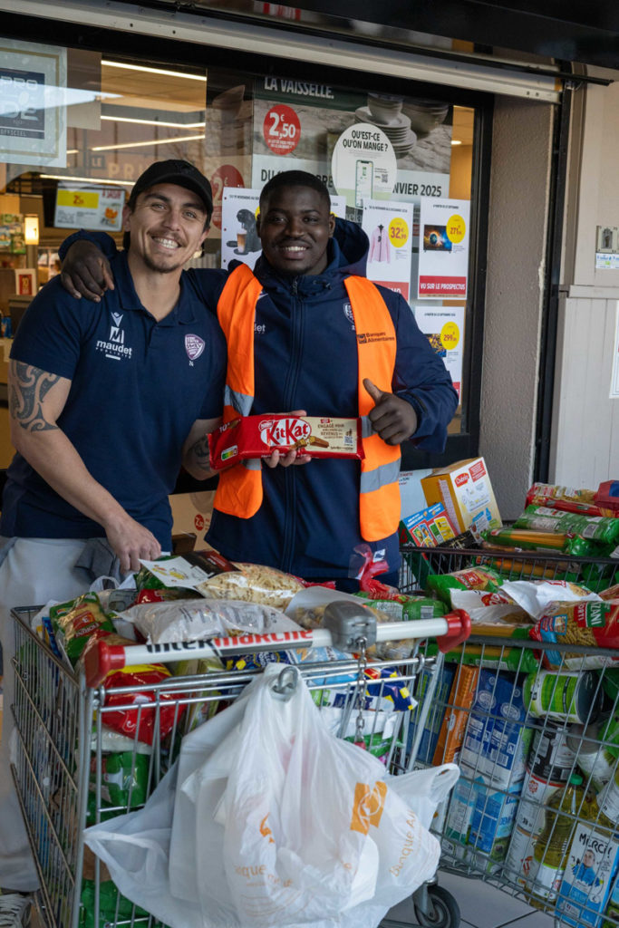 Deux hommes souriants avec chariots remplis de courses.