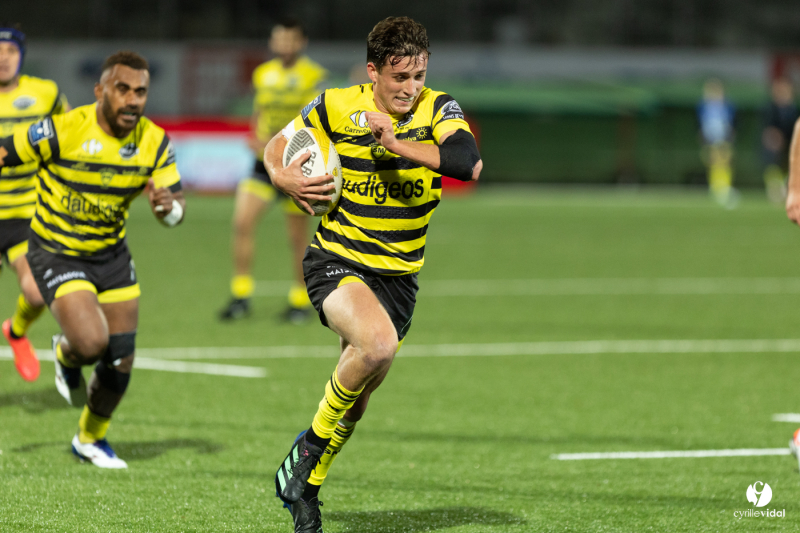 Joueur de rugby courant avec le ballon.